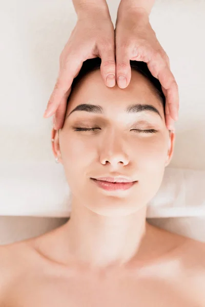 Приваблива жінка отримує масаж обличчя з закритими очима в спа-центрі — стокове фото