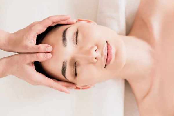 Attractive asian woman getting face massage with closed eyes at spa — Stock Photo