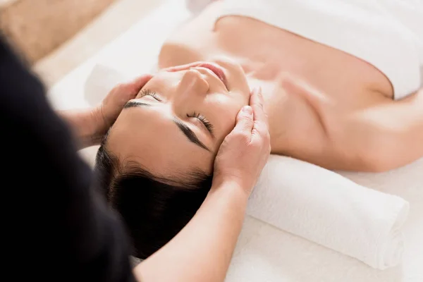 Красивая азиатская женщина получает массаж лица с закрытыми глазами в спа — стоковое фото