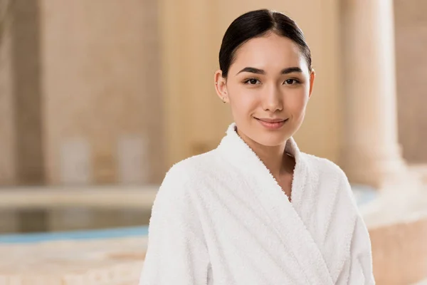 Beautiful asian woman in bathrobe looking at camera at spa — Stock Photo