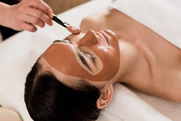 Cropped view of beautician applying mask on woman face — Stock Photo