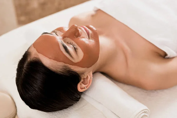 Jolie femme couchée avec masque sur le visage au spa — Photo de stock