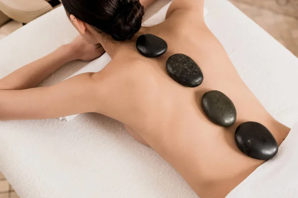 Rückenansicht einer Frau, die im Wellnessbereich eine Steinmassage bekommt — Stockfoto