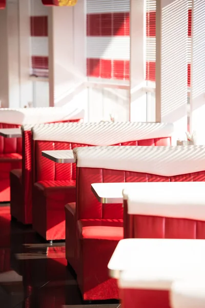 Interior of cafe with red sofas and white tables — Stock Photo