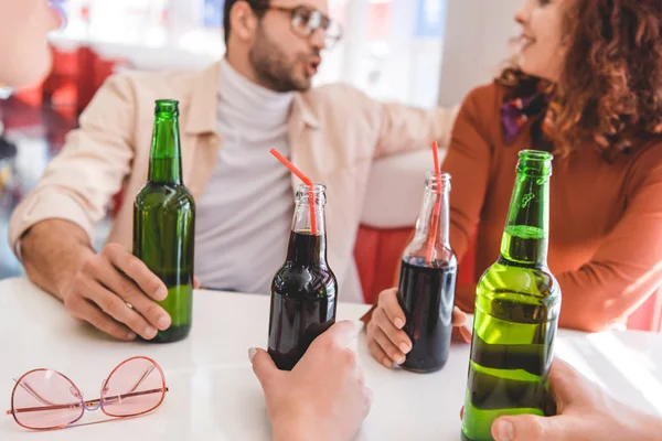 Enfoque selectivo de botellas de vidrio con celebración de bebidas por amigos - foto de stock