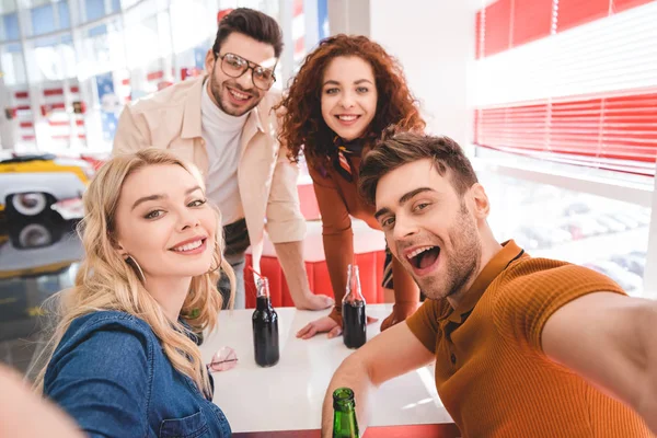 Selektiver Fokus lächelnder gutaussehender und attraktiver Freunde mit Glasflaschen mit Limonade und Bier — Stockfoto