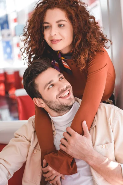 Hermosa mujer y hombre guapo abrazando y sonriendo en la cafetería - foto de stock