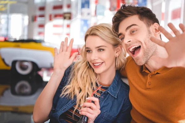Beautiful man and woman smiling, hugging and looking away at cafe — Stock Photo
