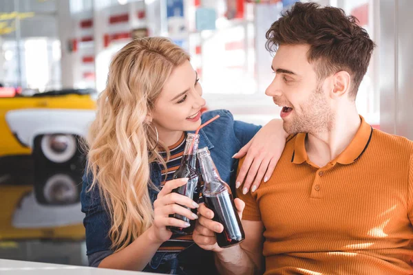 Bella coppia sorridente, abbraccio e tifo con bottiglie di vetro al caffè — Foto stock