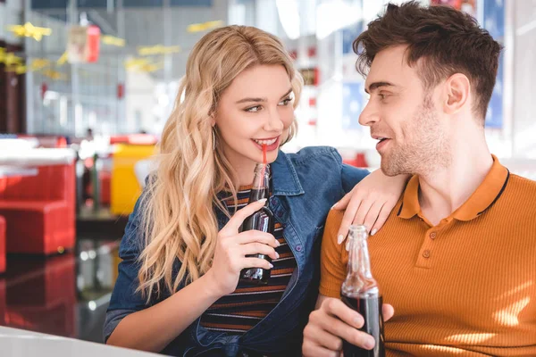 Hermosa pareja sonriendo, abrazando y bebiendo refrescos en la cafetería - foto de stock