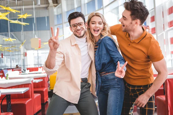 Smiling, beautiful and handsome friends hugging and showing peace sign — Stock Photo
