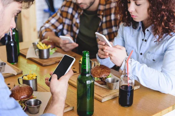 Foco seletivo de amigos usando smartphones com espaço de cópia e tela em branco no café — Fotografia de Stock