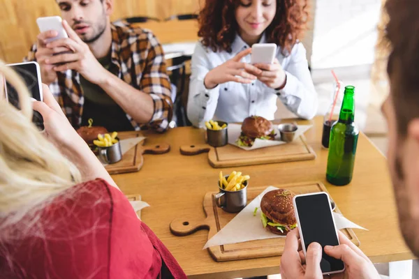 Selective focus of friends using smartphones with copy space and blank screen at cafe — Stock Photo