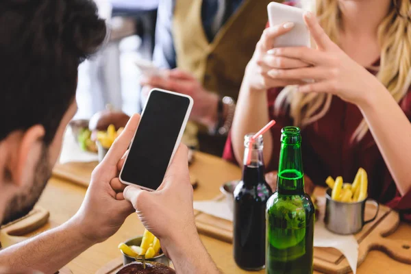 Enfoque selectivo de amigos que utilizan teléfonos inteligentes con espacio de copia en la cafetería - foto de stock