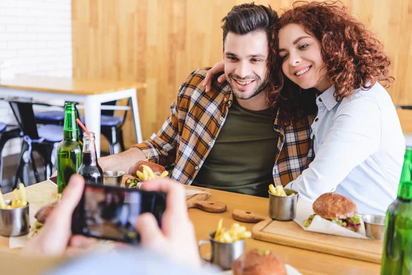 Messa a fuoco selettiva di bella e sorridente coppia in posa per la foto al caffè — Foto stock