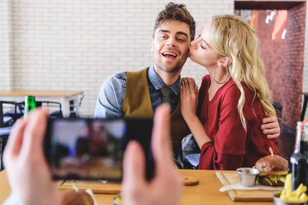 Selective focus of beautiful and kissing couple posing for photo at cafe — Stock Photo