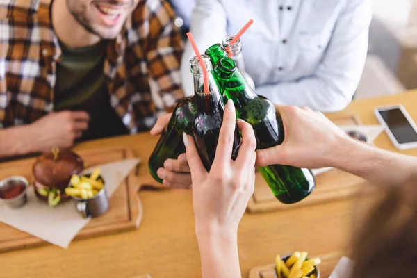 Selective focus of glass bottles with beverage holding by friends — Stock Photo