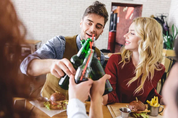 Selektiver Fokus schöner und schöner Freunde, die mit Glasflaschen im Café jubeln — Stockfoto