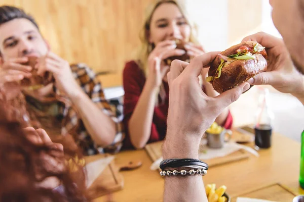 Selective focus of tasty burger holding by man at cafe — Stock Photo
