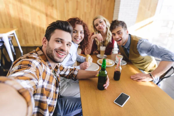 Enfoque selectivo de guapos y hermosos amigos sonriendo y mirando a la cámara - foto de stock