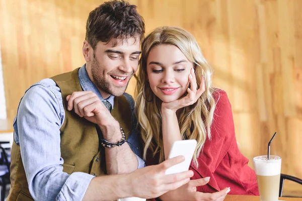 Handsome man and beautiful woman using smartphone at cafe — Stock Photo