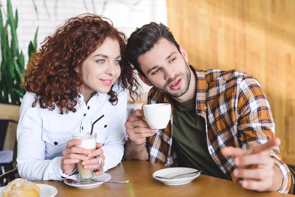 Foco seletivo de casal bonito e sorridente beber café e olhar para longe — Fotografia de Stock