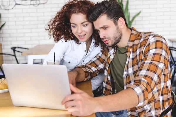 Attractive woman and handsome man hugging and using laptop — Stock Photo