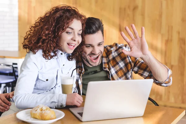 Mulher bonita e homem bonito abraçando, usando laptop e sorrindo — Fotografia de Stock