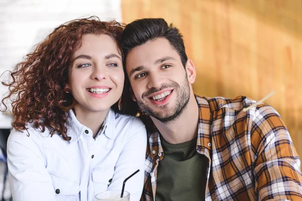 Beautiful man and woman smiling and looking away at cafe — Stock Photo