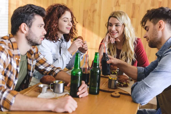 Вибірковий фокус красивих і привабливих друзів, які розмовляють, посміхаються і їдять в кафе — стокове фото