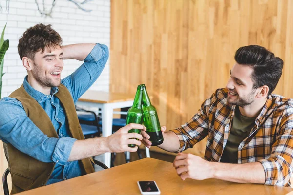 Handsome and smiling friends cheering with glass bottles of beer — Stock Photo