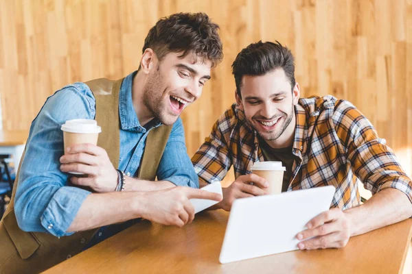 Beaux hommes tenant des bouteilles de bière en verre et utilisant une tablette numérique — Photo de stock