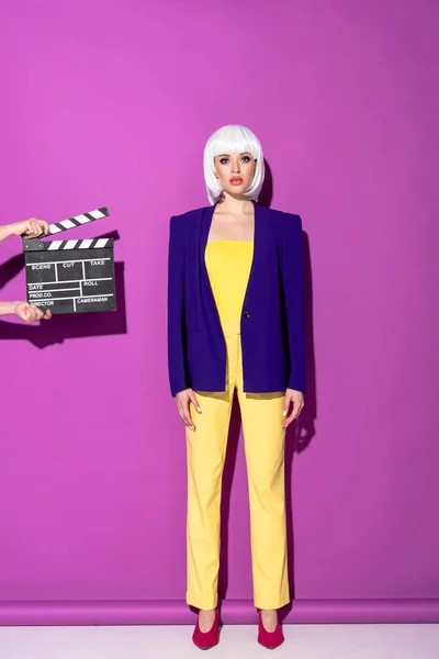 Гламурная женщина в белом парике стоит на фиолетовом фоне — стоковое фото