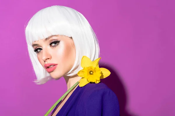 Pretty young woman in white wig holding flower on purple background — Stock Photo