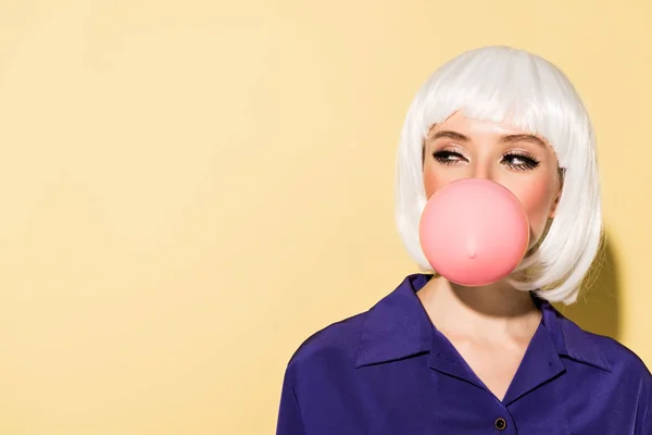 Girl in white wig chewing bubble gum on yellow background — Stock Photo