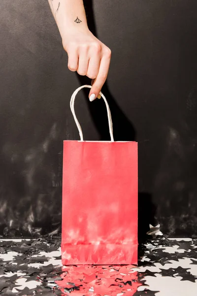 Teilansicht von Mädchen mit Tätowierungen mit rosa Einkaufstasche auf schwarzem Hintergrund — Stockfoto