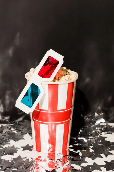 Coupe avec pop-corn et verres 3D sur fond sombre — Photo de stock