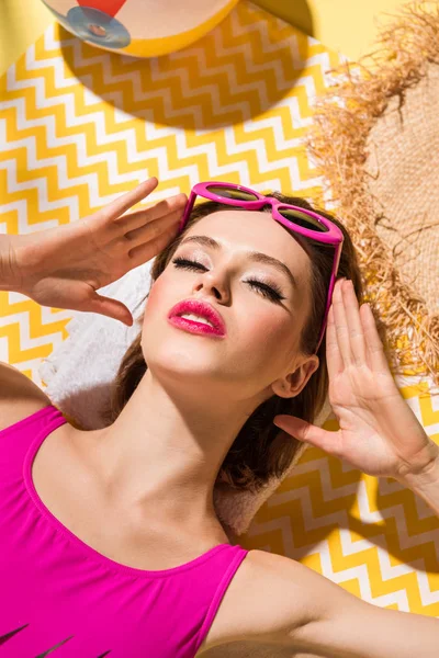 Sensual young woman lying with closed eyes on yellow surface — Stock Photo