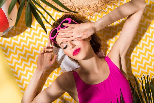 Vue du dessus de la femme détendue dans des lunettes de soleil couché avec les yeux fermés sur la surface de zigzag — Photo de stock