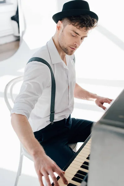 Bel pianista in camicia bianca e cappello nero che suona il pianoforte — Foto stock