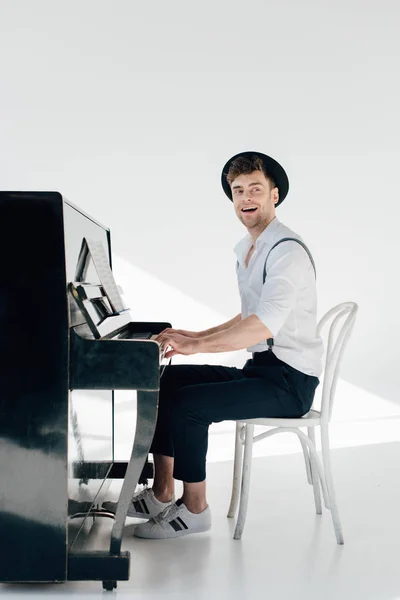 Вдохновленный пианист в белой рубашке и черной шляпе, играющий на пианино — стоковое фото