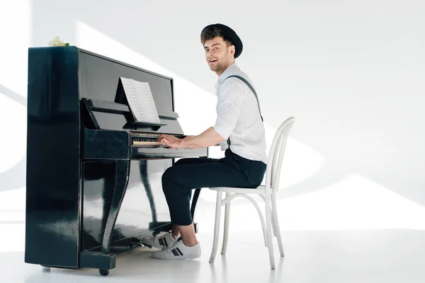 Pianista sonriente con ropa de moda tocando el piano - foto de stock
