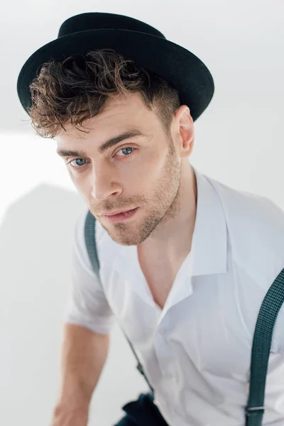 Selective focus of handsome dreamy man in white shirt and black hat — Stock Photo