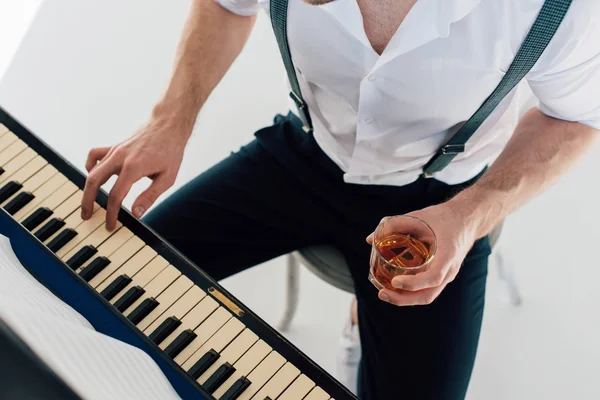 Vista cortada de pianista segurando copo de bebida alcoólica enquanto tocava piano — Fotografia de Stock