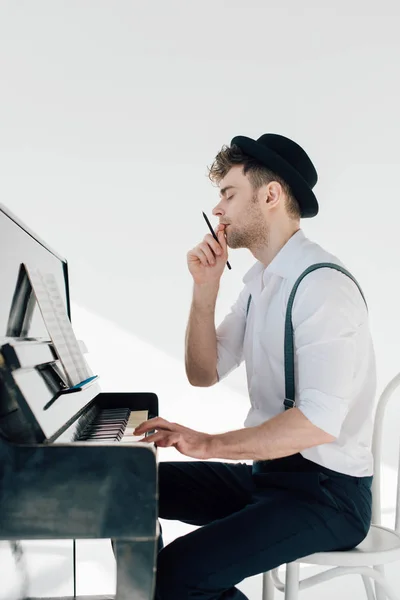 Красивый мужчина компилирует музыку, сидя за роялем — стоковое фото