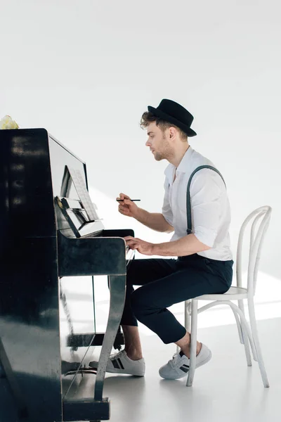 Handsome pianist sitting at piano and composing music — Stock Photo