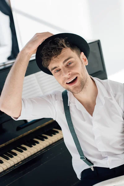 Selective focus of smiling pianist in trendy clothing smiling and looking at camera — Stock Photo