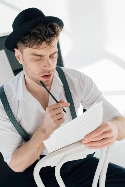 Compositeur réfléchi regardant les feuilles de livres de musique — Photo de stock