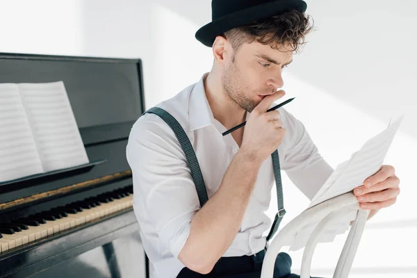 Foyer sélectif de musicien réfléchi tenant des feuilles de livres de musique — Photo de stock