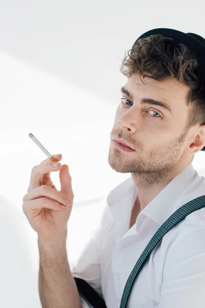 Handsome man holding cigarette and looking at camera — Stock Photo